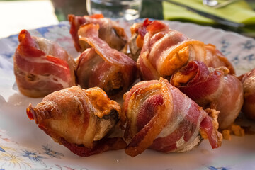 Mushrooms with bacon, grilled or oven baked. Fried bacon. Delicious appetizer. Treat for guests. Blurred background.High quality photo