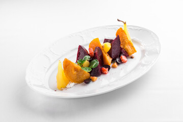 warm salad with baked pumpkin and beetroot on white plate isolated on white background