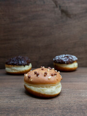 Delicious glazed chocolate donuts on wooden background