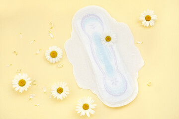 Women's absorbent soft hygienic protective pads with soothing chamomile extract during menstruation on a yellow background with flowers.  gynecological menstruation cycle. flower on menstrual  napkin