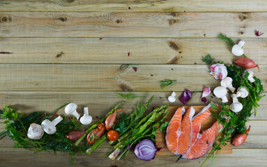 Fresh vegetables, steaks of salmon, mushrooms, greens and spices on wooden background with copyspace