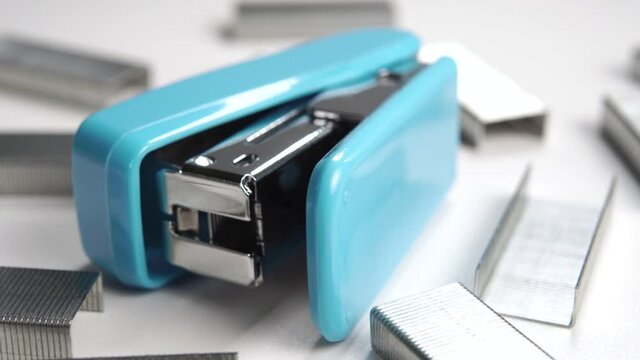Office stapler with staples. Macro shot. Blue plastic handle. Desktop accessories. Rotation