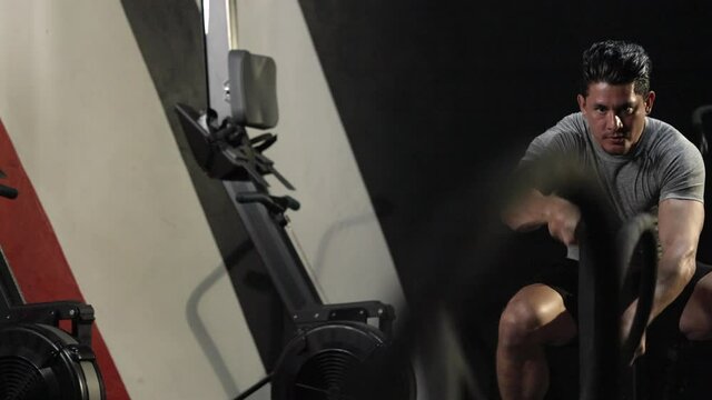 Concept of healthy and sport.Active dedicated motivated male athlete training in gym with battle ropes,determined confident man enjoying bodybuilding achieving goals with healthy lifestyle.4k footage