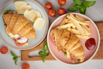 two croissant sandwiches on wooden table, top view, Sandwich with bacon, fried egg. Ham, cheese, bacon, fried egg, tomato, french fries and lettuce served in a plate.