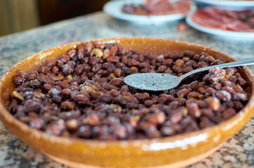 Plato de cacachuetes recien tostados y salados con la cuchara en medio en un plato de barro amarillo