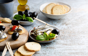 anchovy appetizer with olives. Mediterranean appetizer, anchovy fish in olive oil and herbs in a small bowl.