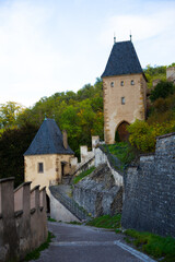 Fototapeta na wymiar View of old road leading to medieval Gothic towers of Karlstejn Castle on autumn day, Czech Republic