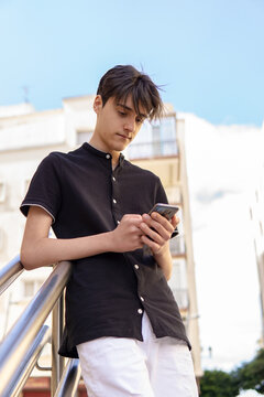 Retrato de un adolescente cauc&aacute;sico usando un smartphone en la ciudad