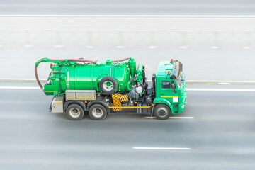 A truck with a tank and a water pumping system drives on the highway.