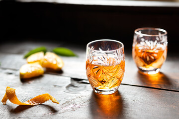 Two glasses with tangerine liqueur on an old wooden background