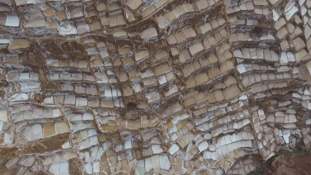 Salt terraces of Maras near Cusco Andes mountain peak, Sacred Valley of the Incas, Peru. (aerial photography)