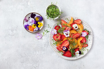 Fresh salad with strawberries, Loquat fruit and edible flowers in a bowl.	