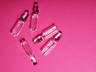 Banner of several ampoules with a clear solution on a pink background, medicine and medicines