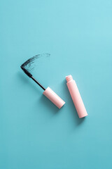 Mascara on blue background top view, makeup product.