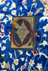Fototapeta na wymiar Islamic book holy Quran with rosary beads and scent bottle on colorful prayer mat,Muslim religious