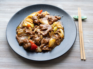 chinese cuisine - stir-fried beef with leeks on black plate on wooden table