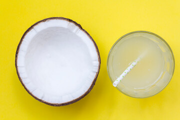 Top view of coconut and coconut water on glass with straw on yellow background