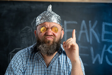 close-up a conspiracy theorist in a protective foil hat with bitcoin coins in his eyes raised his...