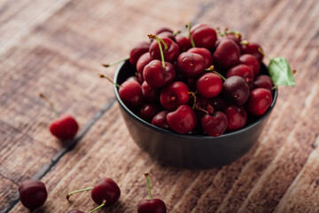 Closeup shot of fresh red cherries on a bowl on a wooden table