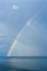 Rainbow over Lake Baikal against the background of rain clouds. Vertical image.