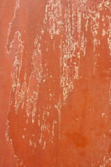 Old wooden panels with peeling red surface with scratches. Vertical image.