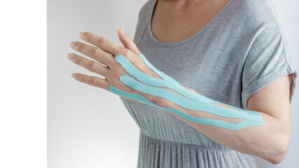 Female arm with blue medical moisture resistant elastic kinesio tape to protect against edema. Hand rehabilitation after operation - obrazy, fototapety, plakaty