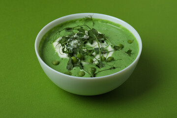 Bowl of pea soup on green background
