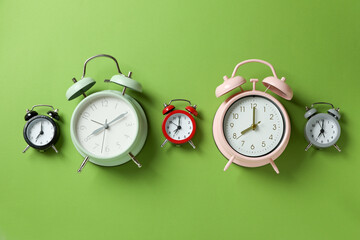 Different multicolor alarm clocks on green background
