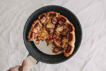 Homemade pizza with sausages and pineapple in a pan.