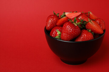 Bowl of fresh strawberry on red background
