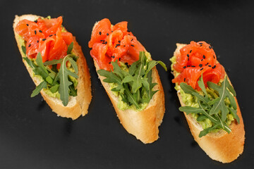 Appetizer tartlets with red caviar and arugula on a black plate. Beautifully decorated catering banquet menu. Food snacks and appetizers for buffet.