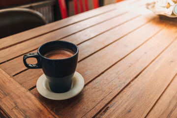 Blue mug of hot chocolate on dark wooden table in a cafe.