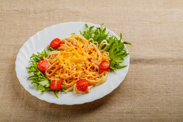 A plate of pasta with cherry tomatoes and cheese on a linen tablecloth.
