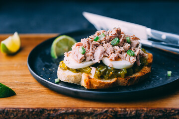 Open sandwich with canned tuna, egg and pickled cucumber dressing served with lime.