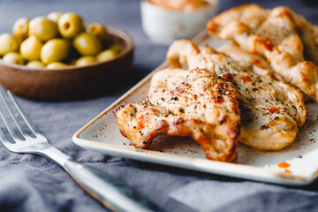 Grilled turkey escalopes with hot sauce on a table.
