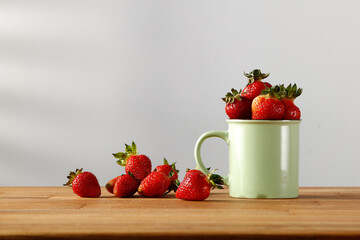 Fresh strawberries on a wooden kitchen table and shadow on the wall 