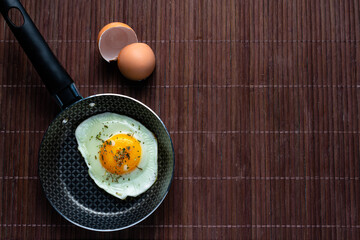 Frying pan with fried egg on a bamboo table