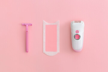 Razor, wax strips and modern electric epilator on pink background