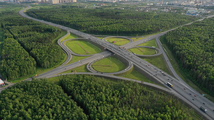 AERIAL. Traffic interchange. Top view of the road, city and forest. Summer video from the drone.