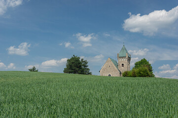 Czech landscape view with crop field and with romanesque church of Archangel Michael. Vitochov village, Czech Republic.