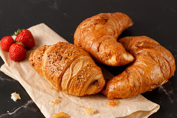 Freshly baked  for breakfast nougat crushed nuts and butter croissants with crumbs and strawberries on paper