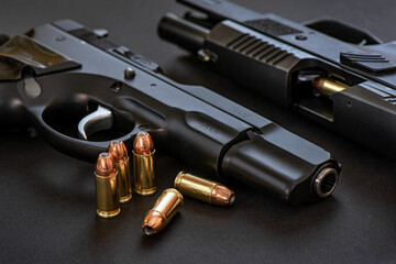 Classic desing pistol and modern deign pistol with 9mm bullets and magazine on black base.