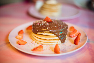Portion of pancakes with chocolate syrup and strawberries on plate close-up. Concept of enjoying food. Proper nutrition. Homemade food.