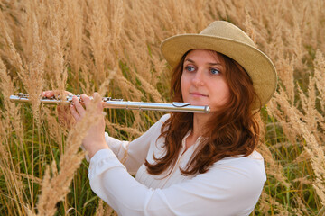 An adult woman with a flute on the autumn grass in a field © Андрей Журавлев