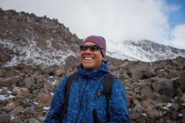 A Mexican smiling hiker with a backpack climbing the Pico de Orizaba