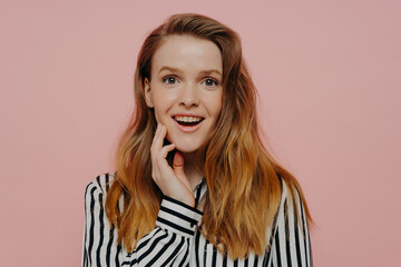 Fototapeta premium Happy young teenage girl demonstrating wow expression while posing over pink background