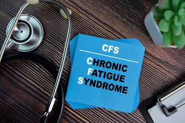 CFS - Chronic Fatigue Syndrome write on sticky notes isolated on Wooden Table. medical concept