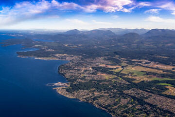 Fototapeta na wymiar Aerial View of Qualicum Beach from an Airplane on the shore of Strait of Georgia in Vancouver Island, British Columbia, Canada. Colorful Blue Sky Art Render.