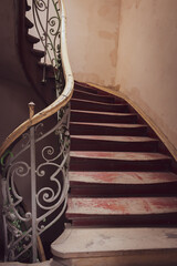 Vintage wooden staircase with iron rail. Old circular stairway in abandoned historical building....