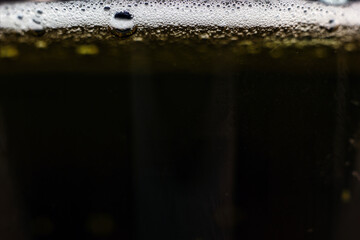 Naklejka na ściany i meble Close-up dark beer with foam and bubbles formed at the edge.